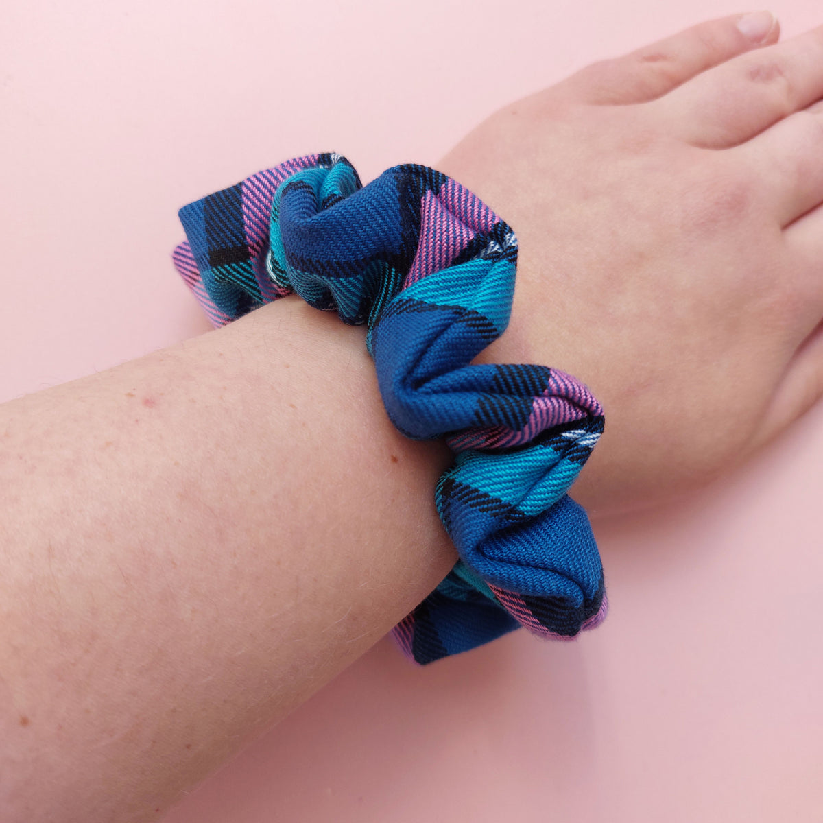 Regular hair scrunchie in a blue, pink and turquoise tartan pattern.