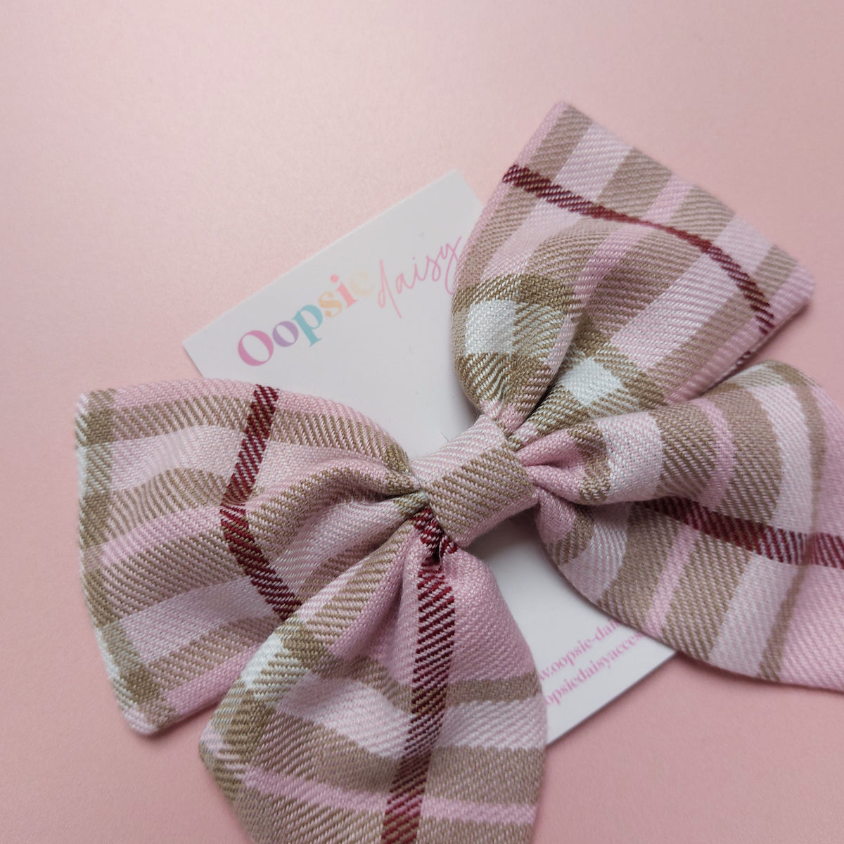 Light pink tartan hair bow with beige, white and burgundy checks.
