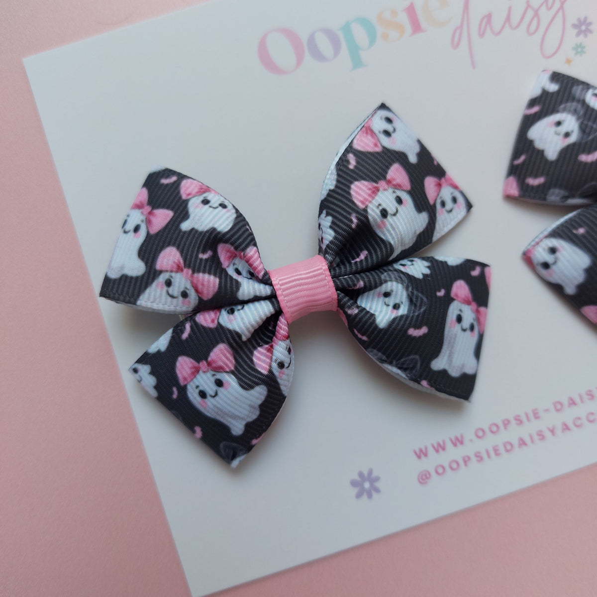 Pair of bow ribbon hair bows with a black background featuring white ghosts wearing pink bows