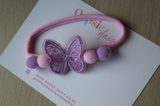 Pink hairband with butterfly and pom-poms