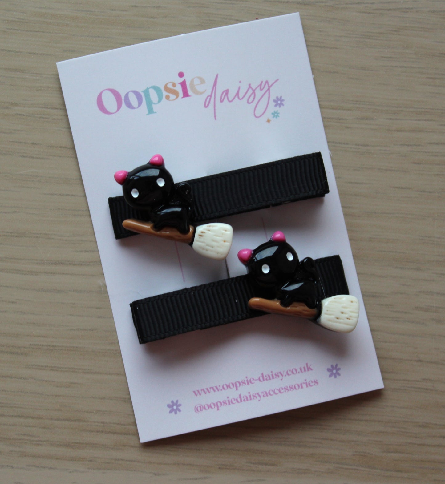 Black hair clips with halloween themed cat on a broomstick