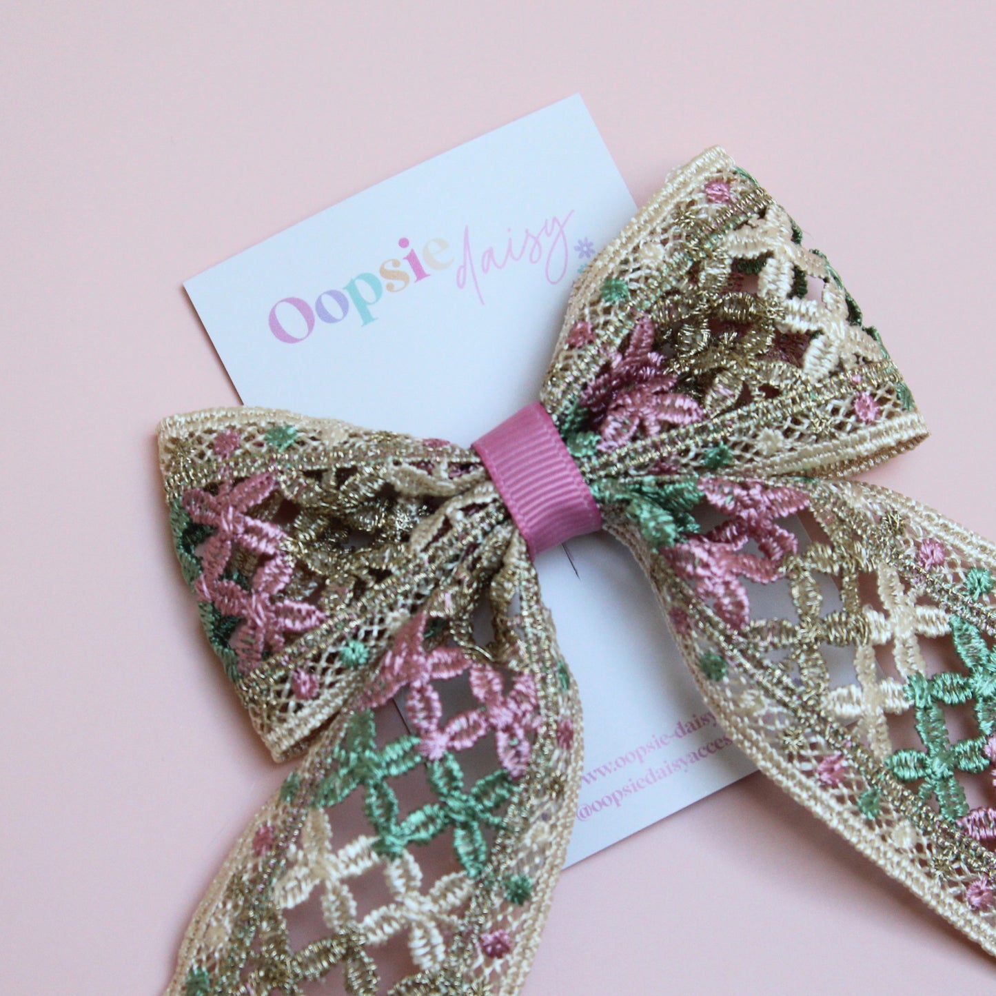 Hair bow with pink, green and gold shimmer embroidered crisscross pattern