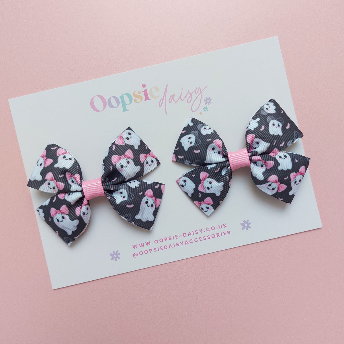Pair of bow ribbon hair bows with a black background featuring white ghosts wearing pink bows