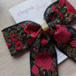 Embroidered hair bow with a festive touch of red and gold