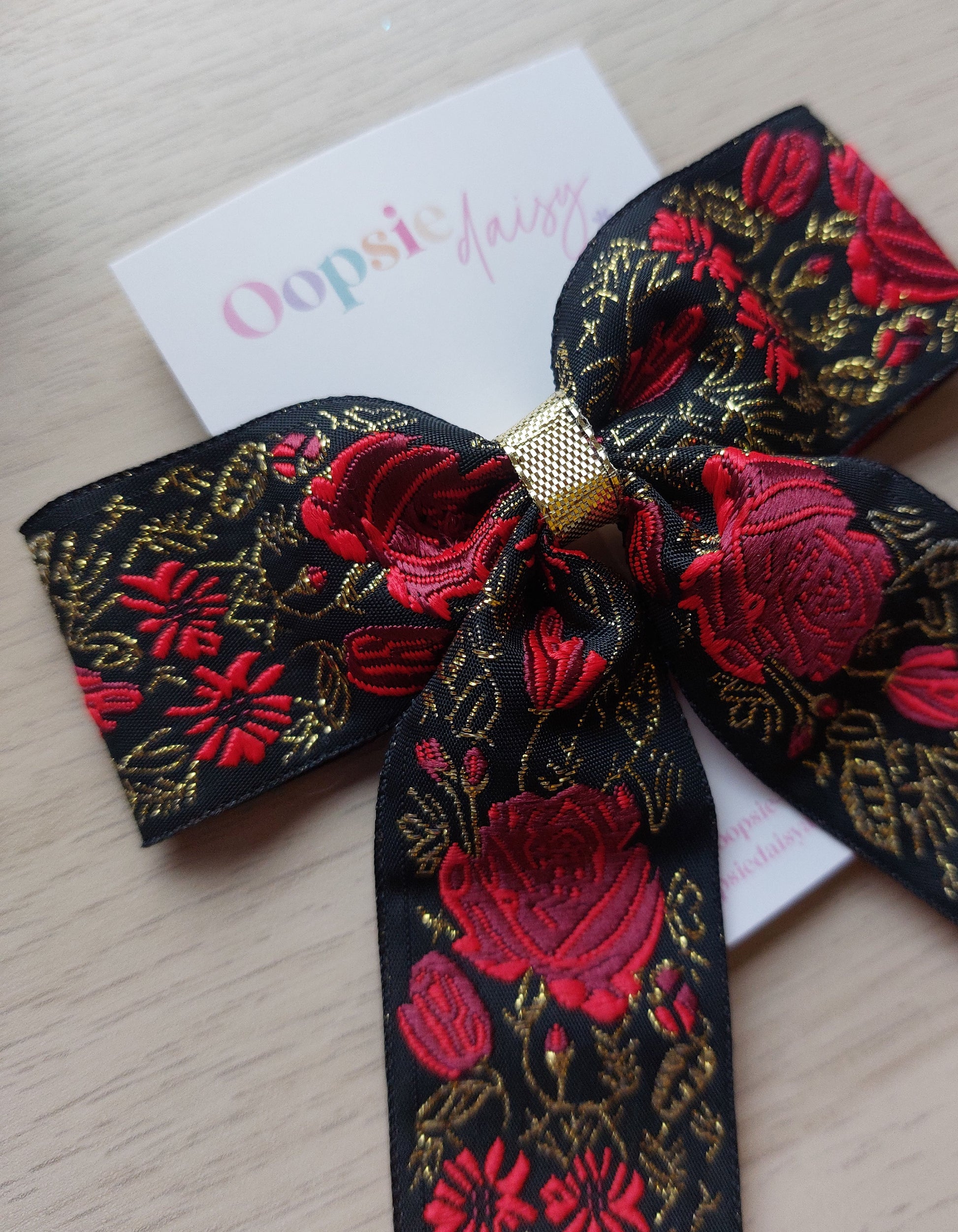 Embroidered hair bow with a festive touch of red and gold