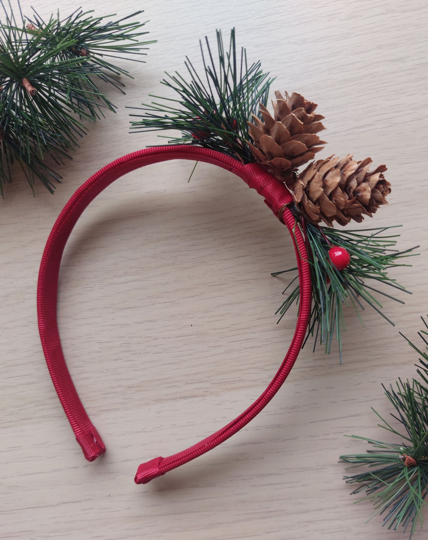 Red festive headband with pine cones and green foliage