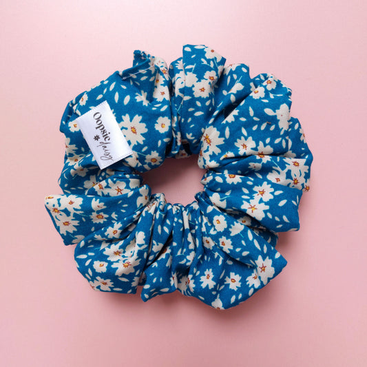 Oversized hair scrunchie with a bold bright blue background and white flowers. 