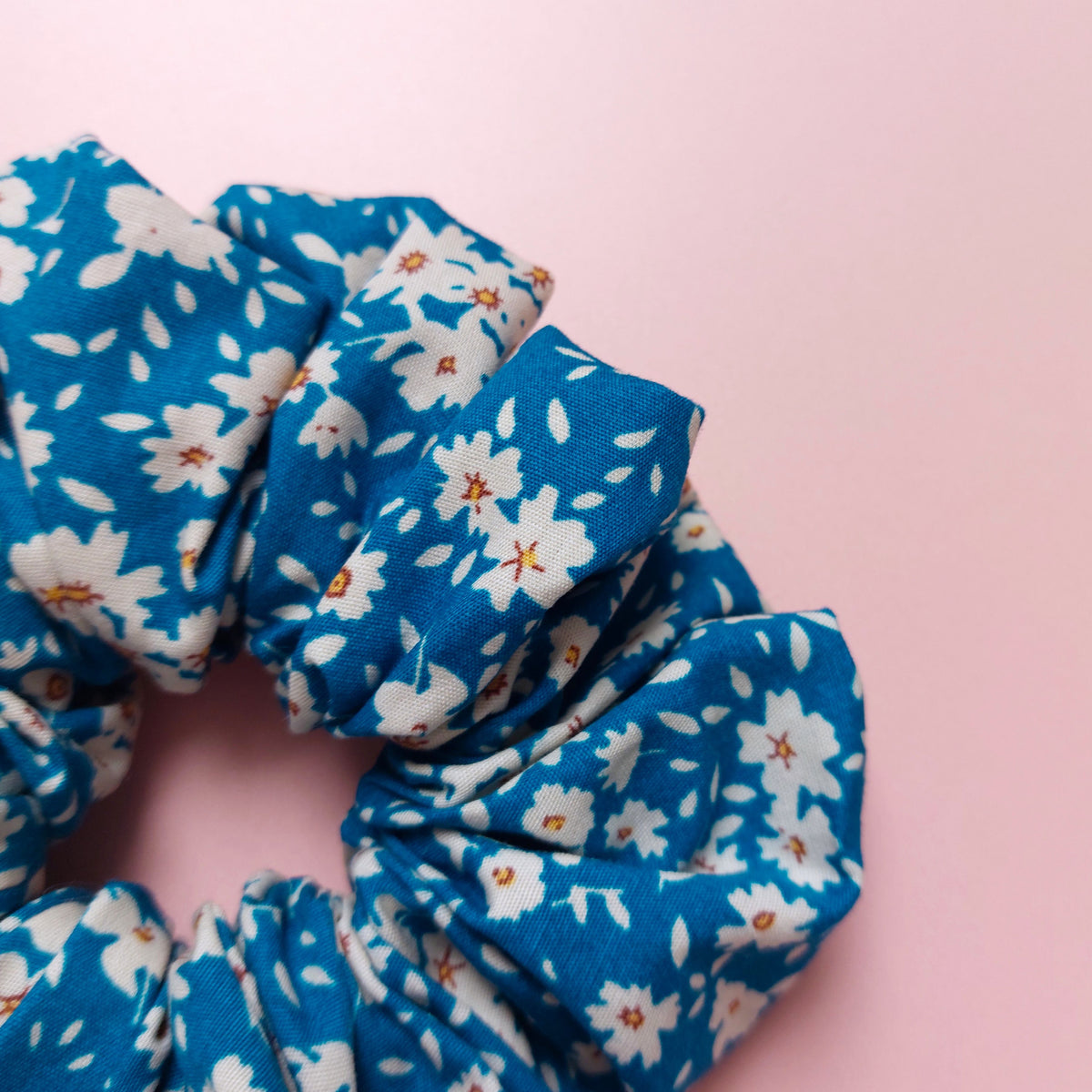Oversized hair scrunchie with a bold bright blue background and white flowers. 