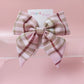 Light pink tartan hair bow with beige, white and burgundy checks. 