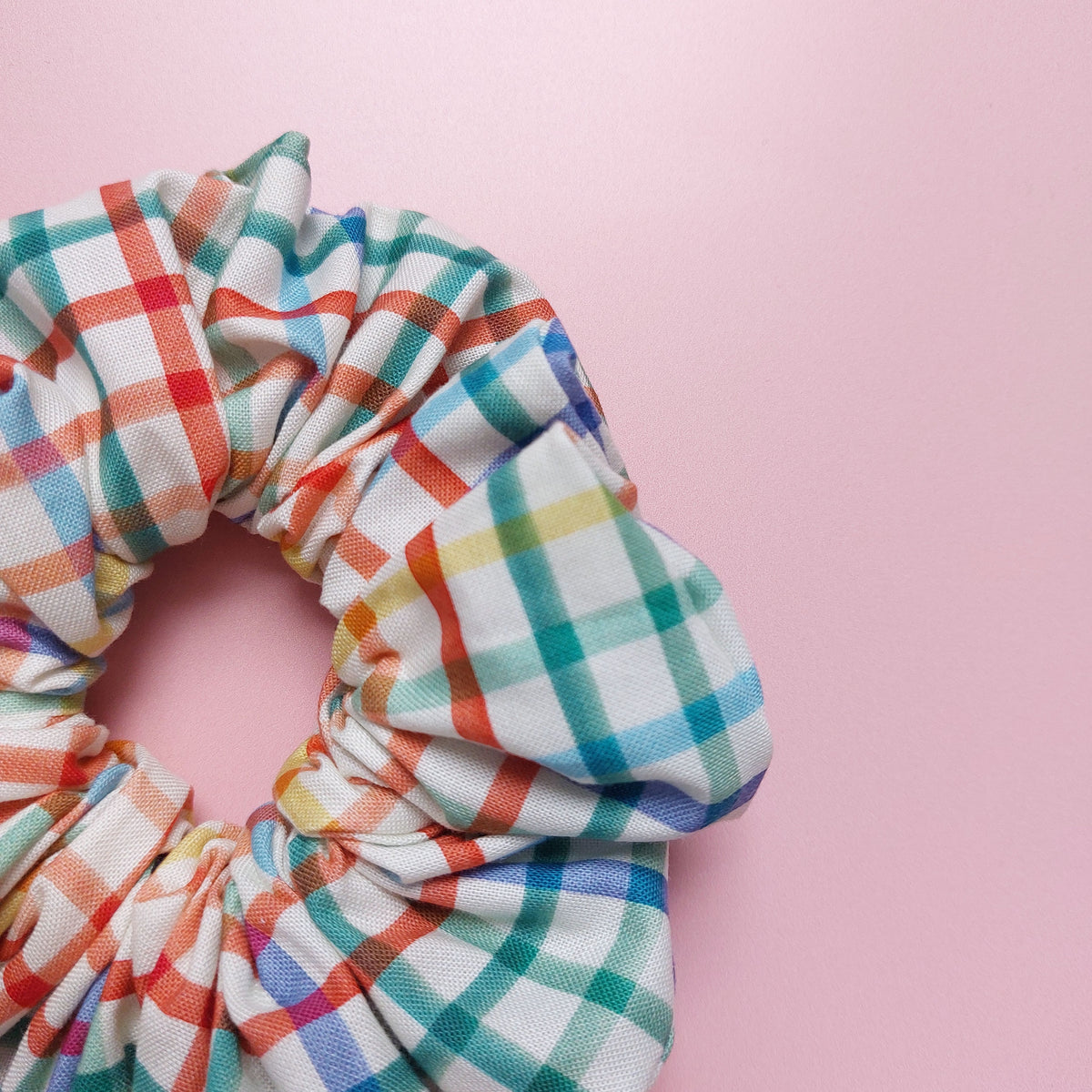 Multicolour check oversized hair scrunchie. Neutral background with red, blue, yellow and green checks. 