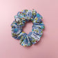 Floral scrunchie with ditsy pattern. Purple flowers with smaller yellow flowers and green leaves. 