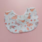 Baby bib with a light green and white background. Features woodland animal motifs, mushrooms and leaves throughout. 
