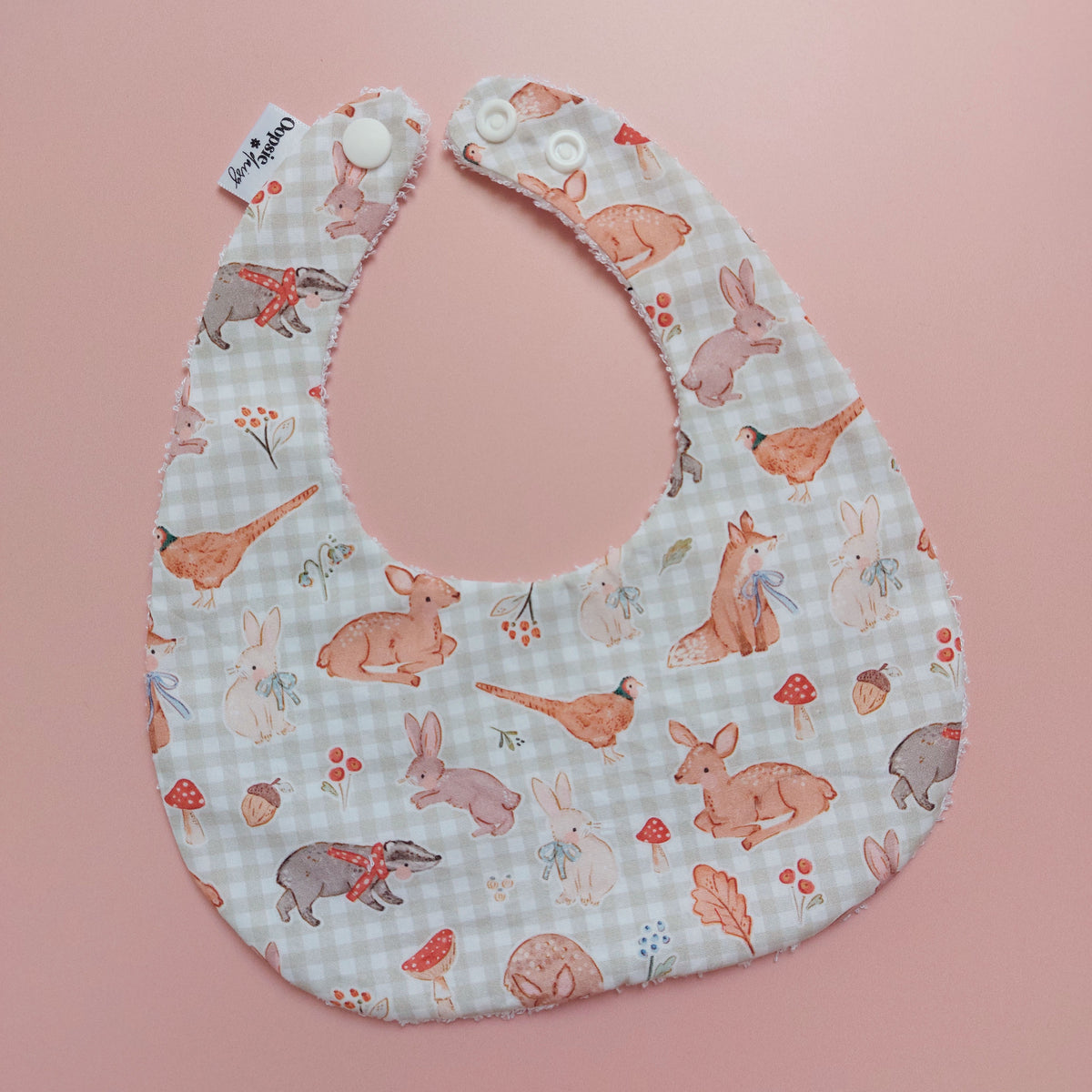 Baby bib with a light green and white background. Features woodland animal motifs, mushrooms and leaves throughout. 