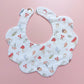 Scallop edged baby bib in white with autumnal pattern. Featuring mushrooms, acorns, leaves and autumnal flowers. 
