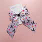 A satin hair bow with a bat pattern accented with small colourful flowers.