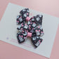 Pair of bow ribbon hair bows with a black background featuring white ghosts wearing pink bows