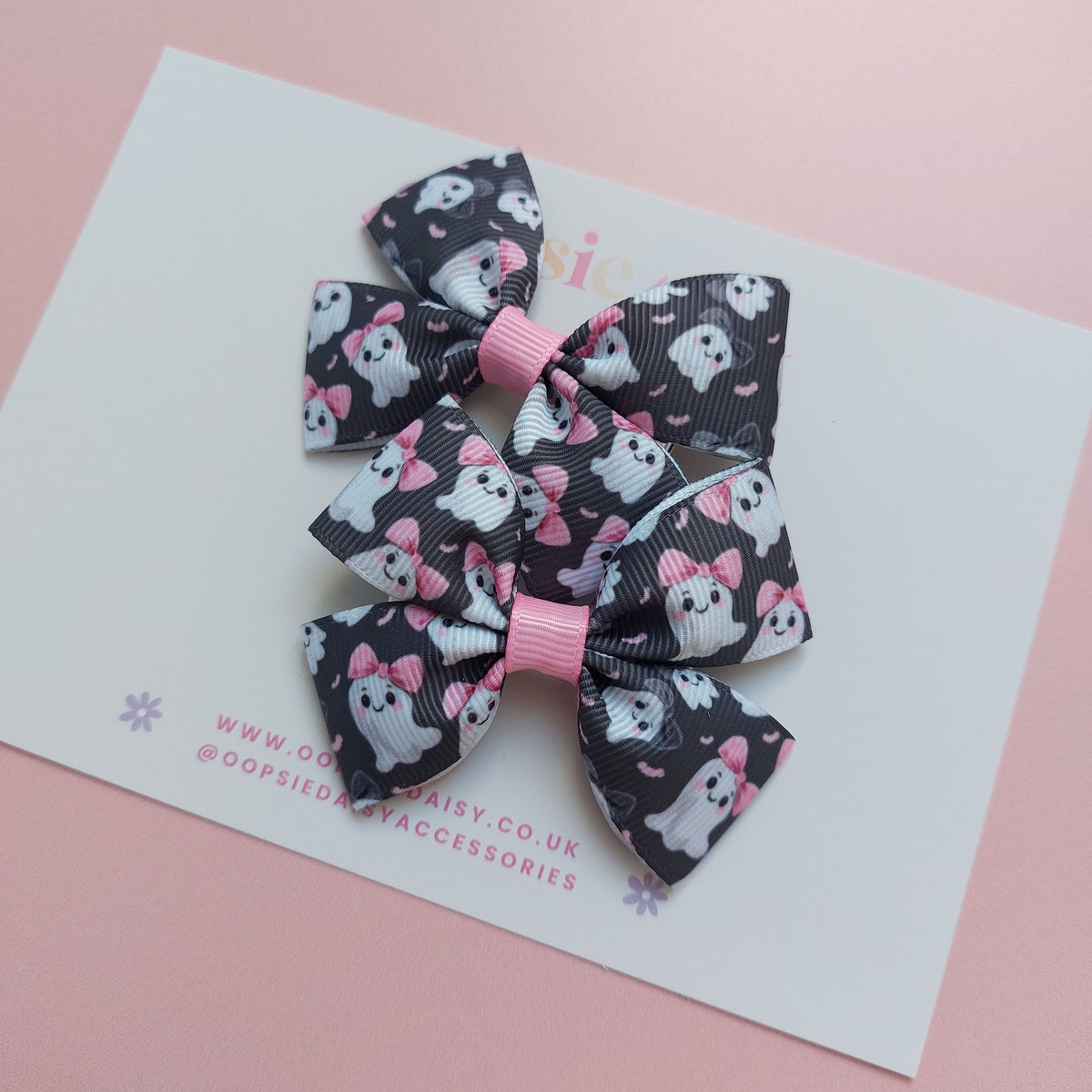 Pair of bow ribbon hair bows with a black background featuring white ghosts wearing pink bows