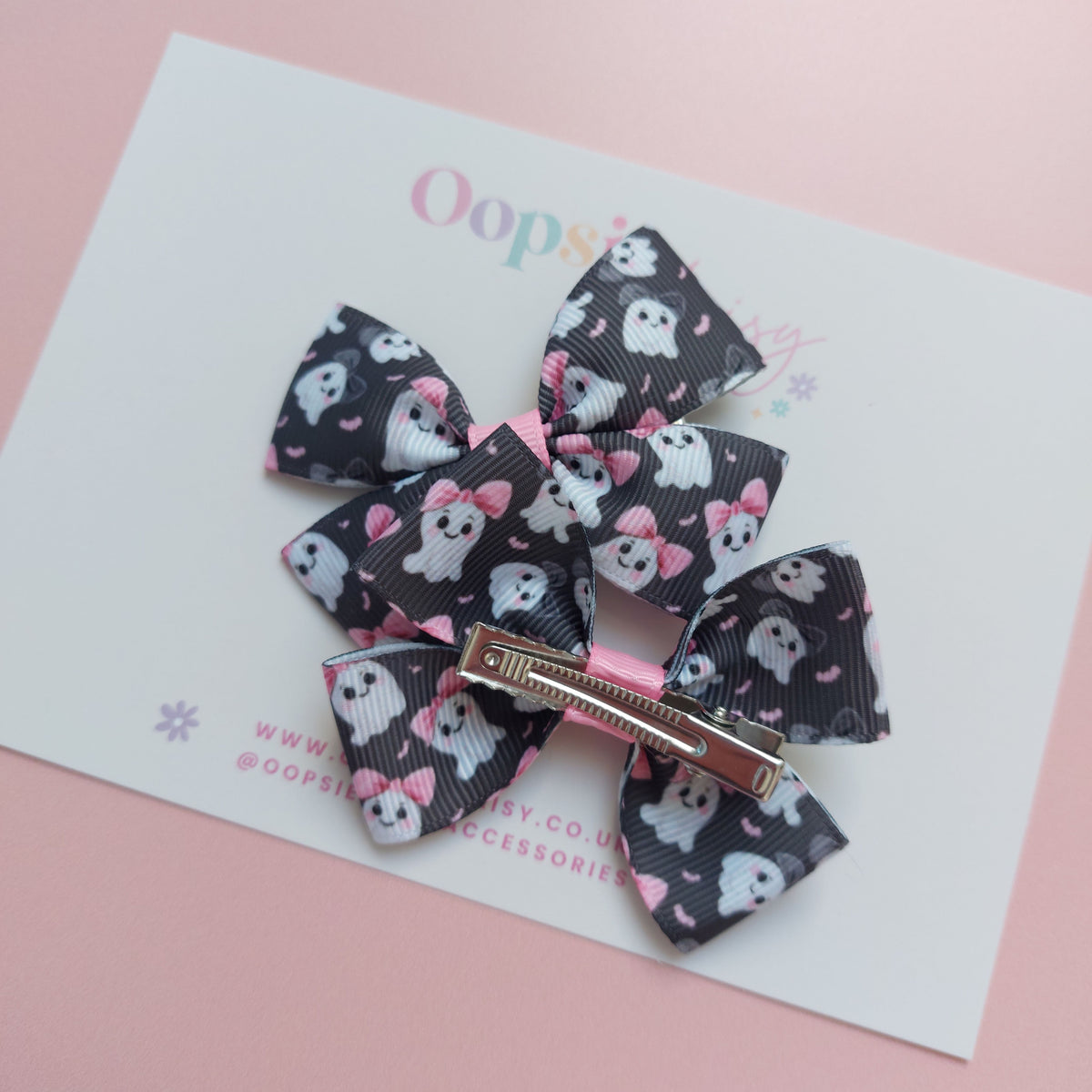 Pair of bow ribbon hair bows with a black background featuring white ghosts wearing pink bows