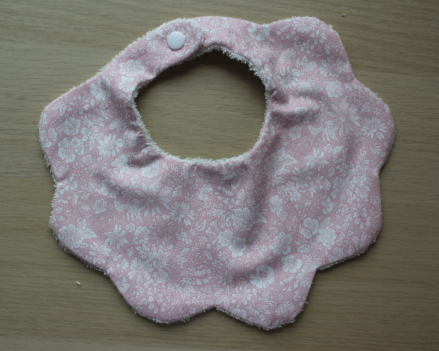 Baby bib with scallop shape and subtle flowers