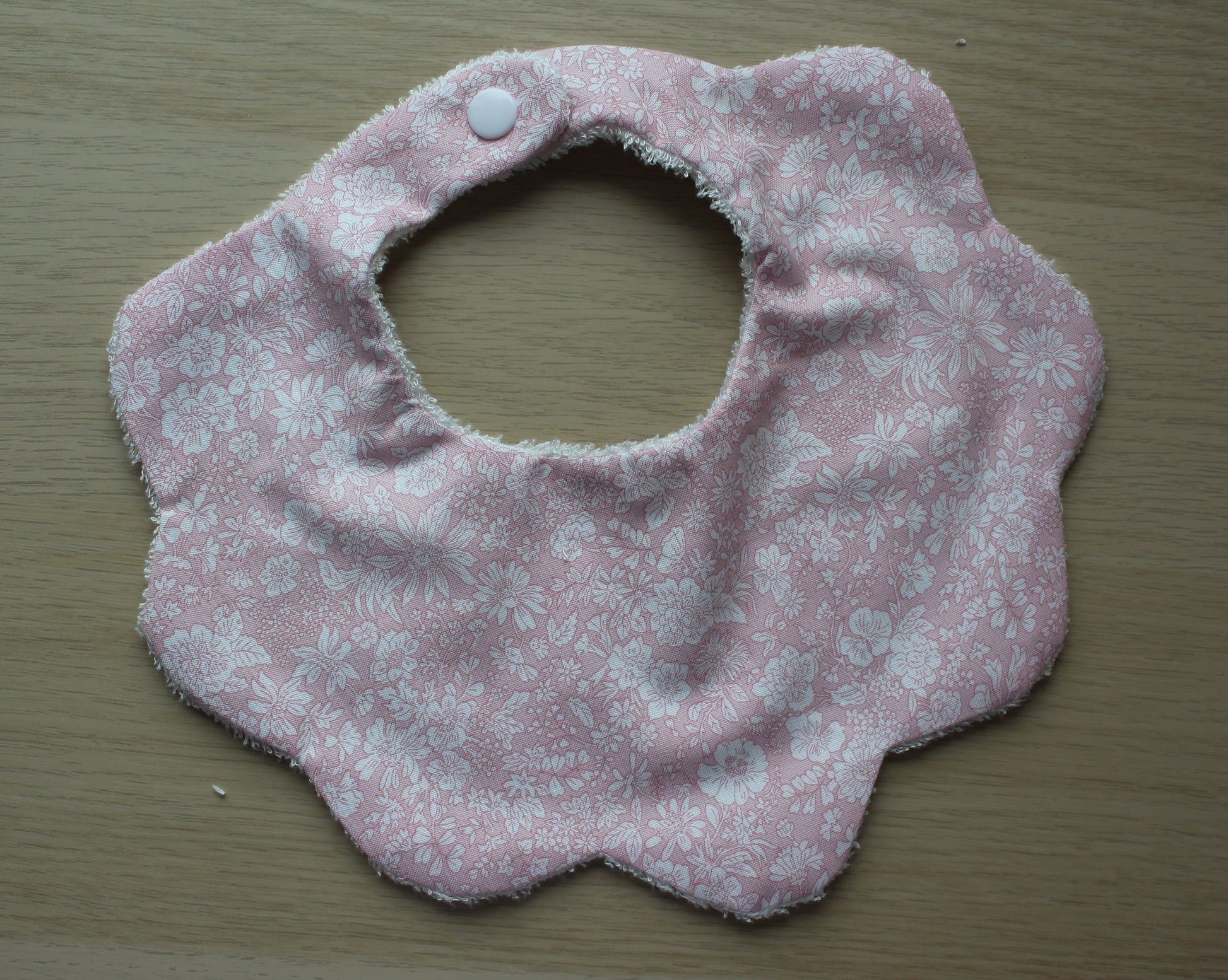 Baby bib with scallop shape and subtle flowers