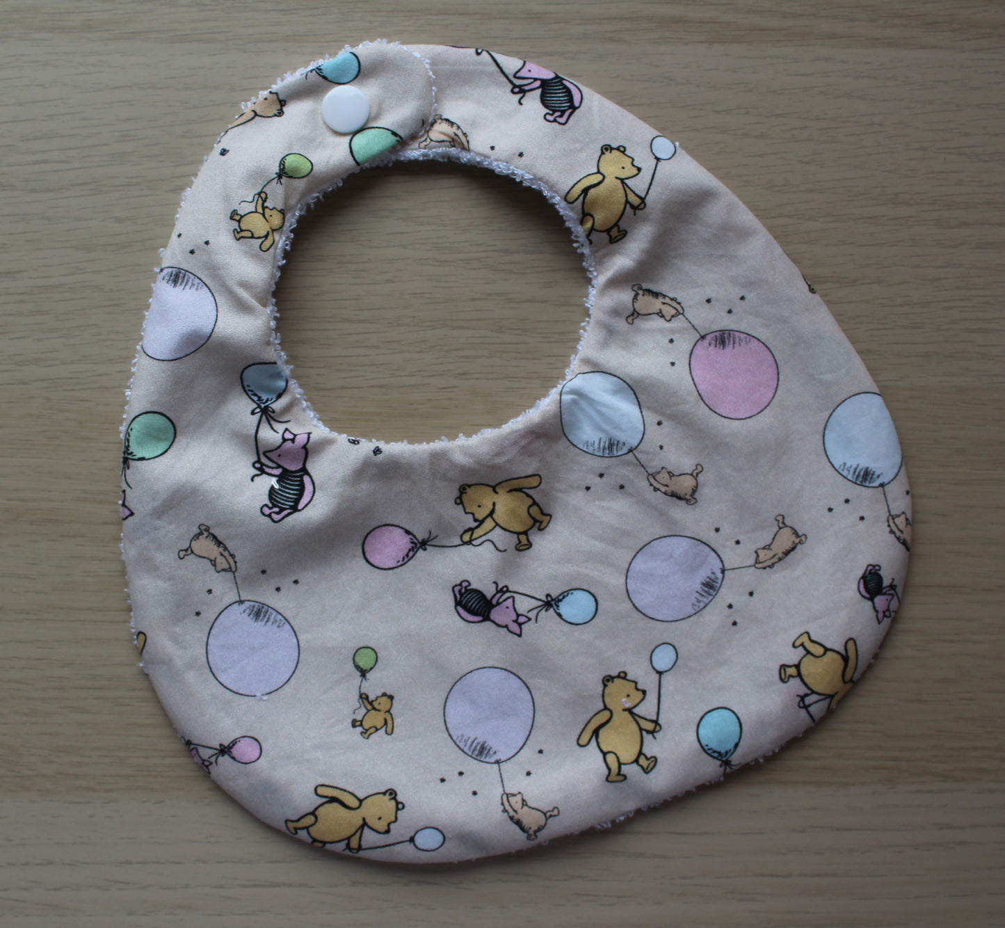 Rounded baby bib with winnie the pooh design