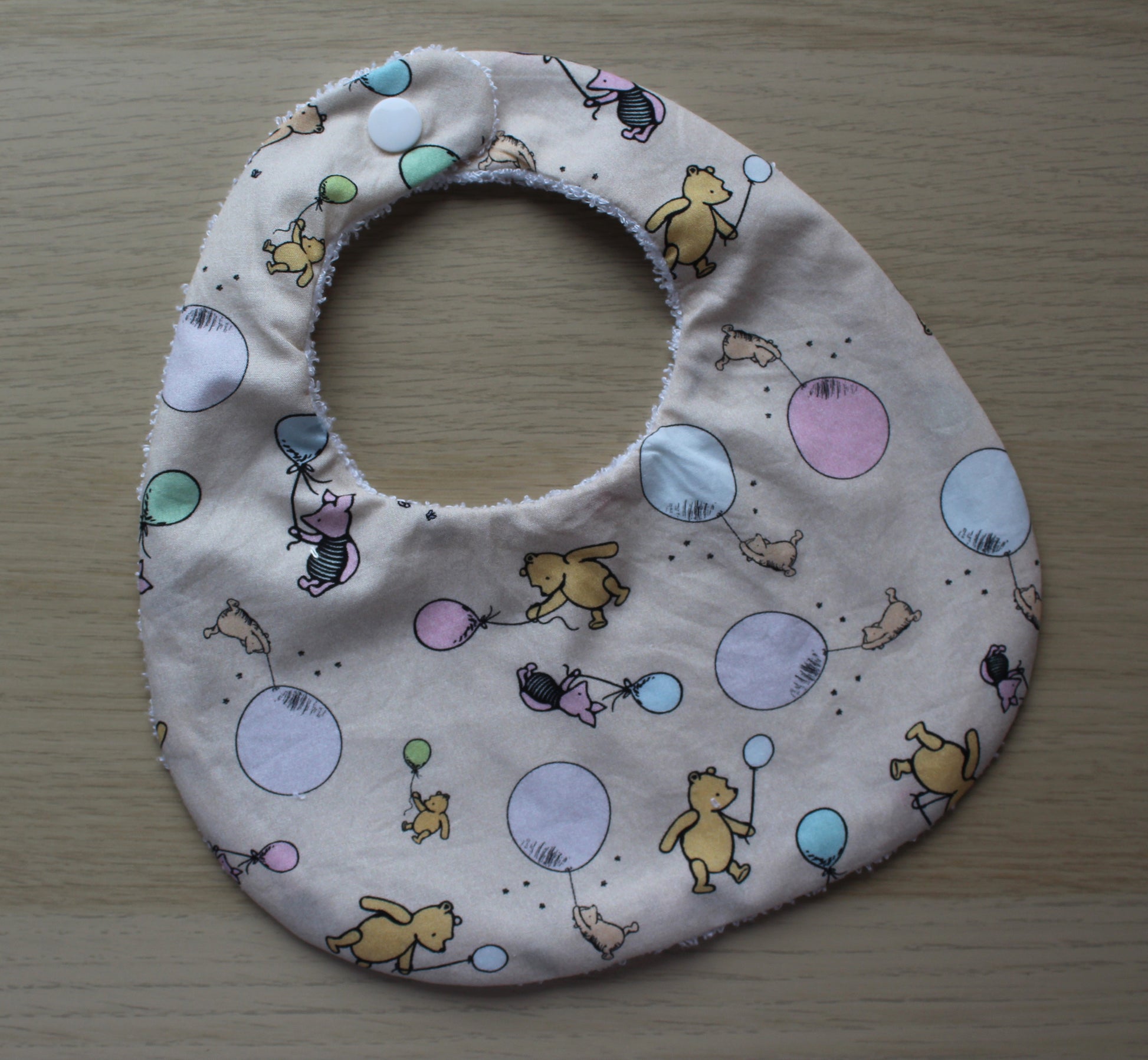 Rounded baby bib with winnie the pooh design