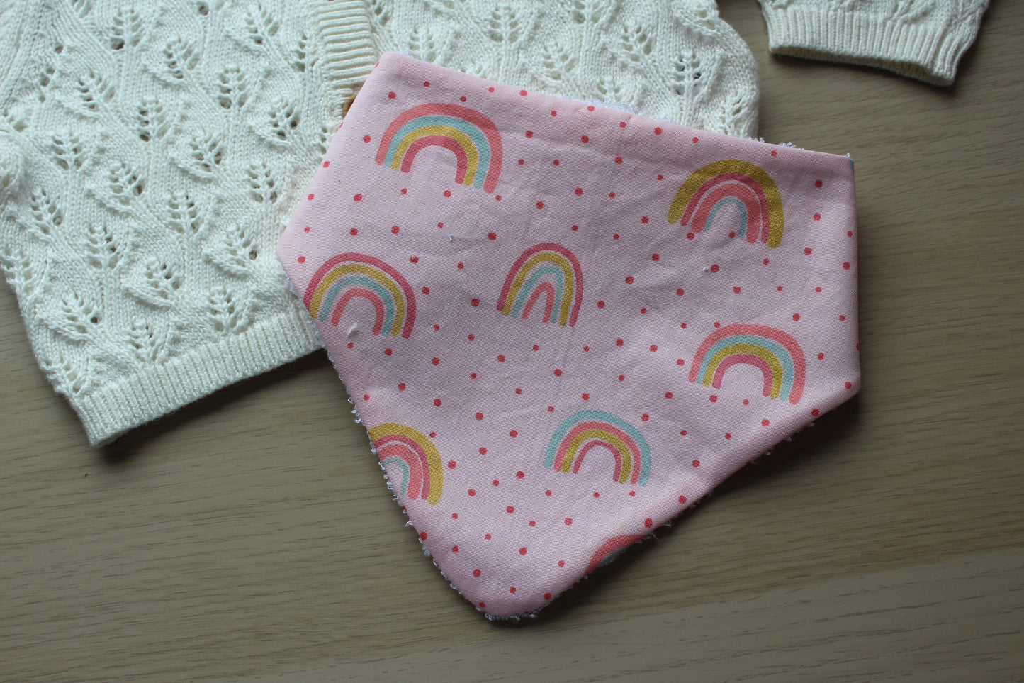 Pink dribble baby bib with rainbow polka dot design