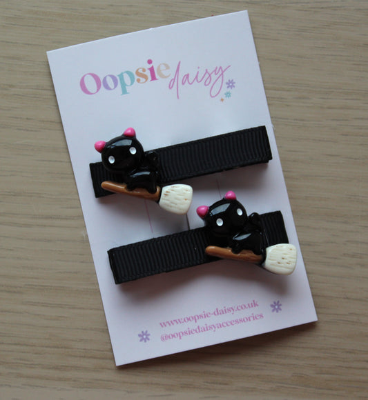 Black hair clips with halloween themed cat on a broomstick