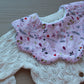 Pink baby bib in scallop shape with festive design