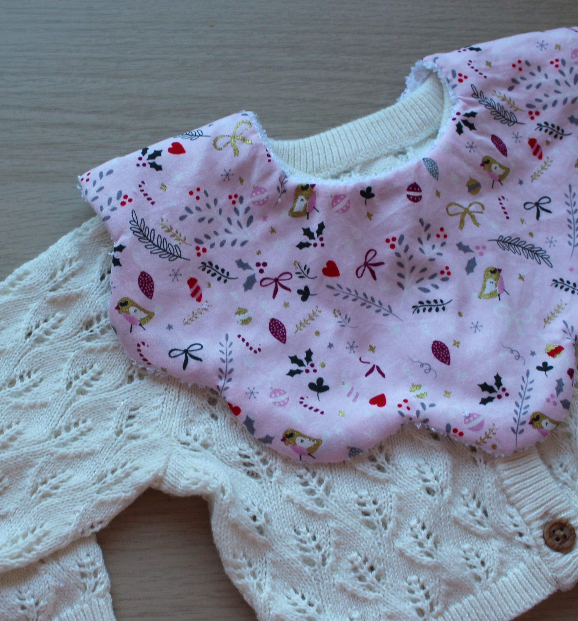 Pink baby bib in scallop shape with festive design