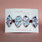 Two bow hair clips with flower pattern in burgundy and pink with green leaves