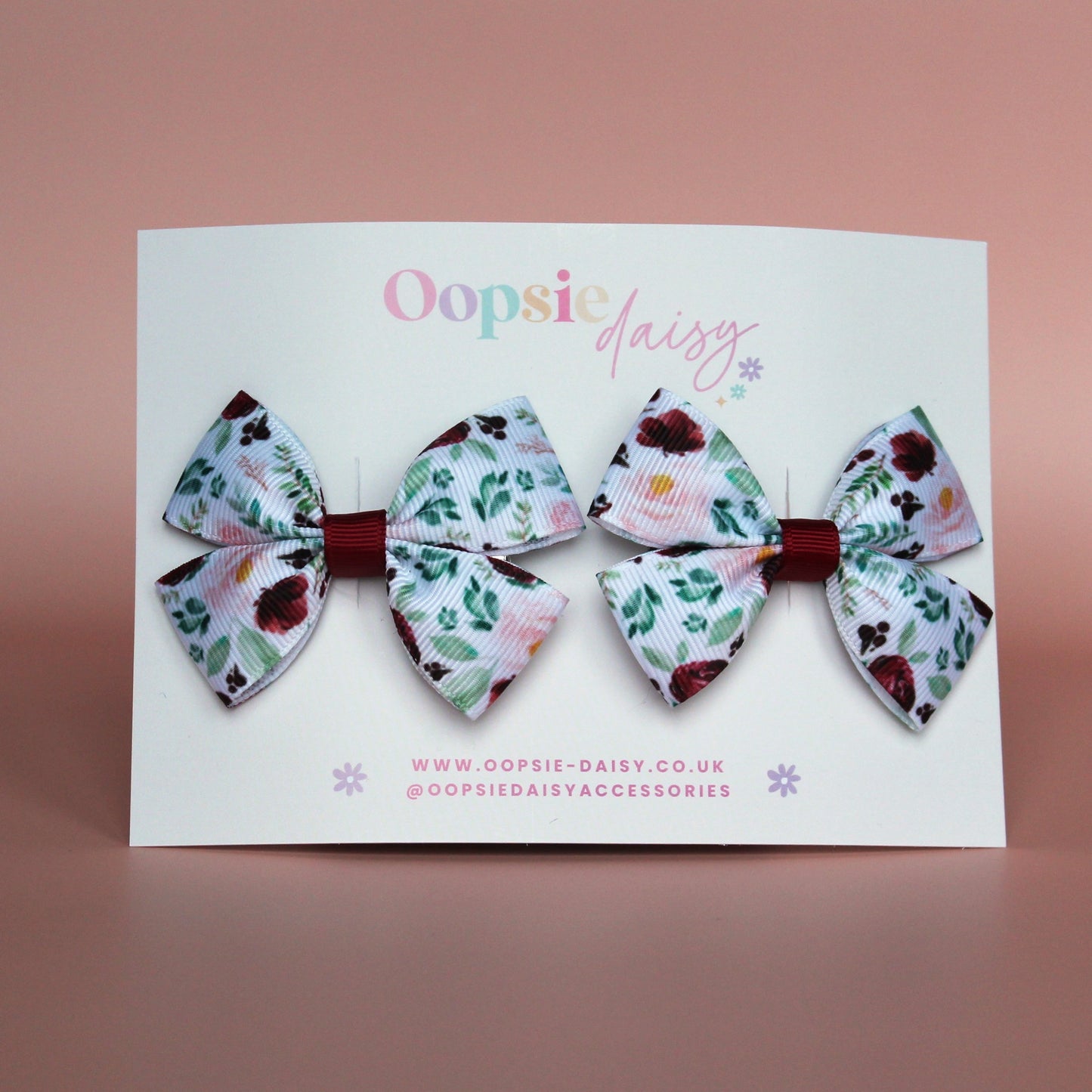 Two bow hair clips with flower pattern in burgundy and pink with green leaves