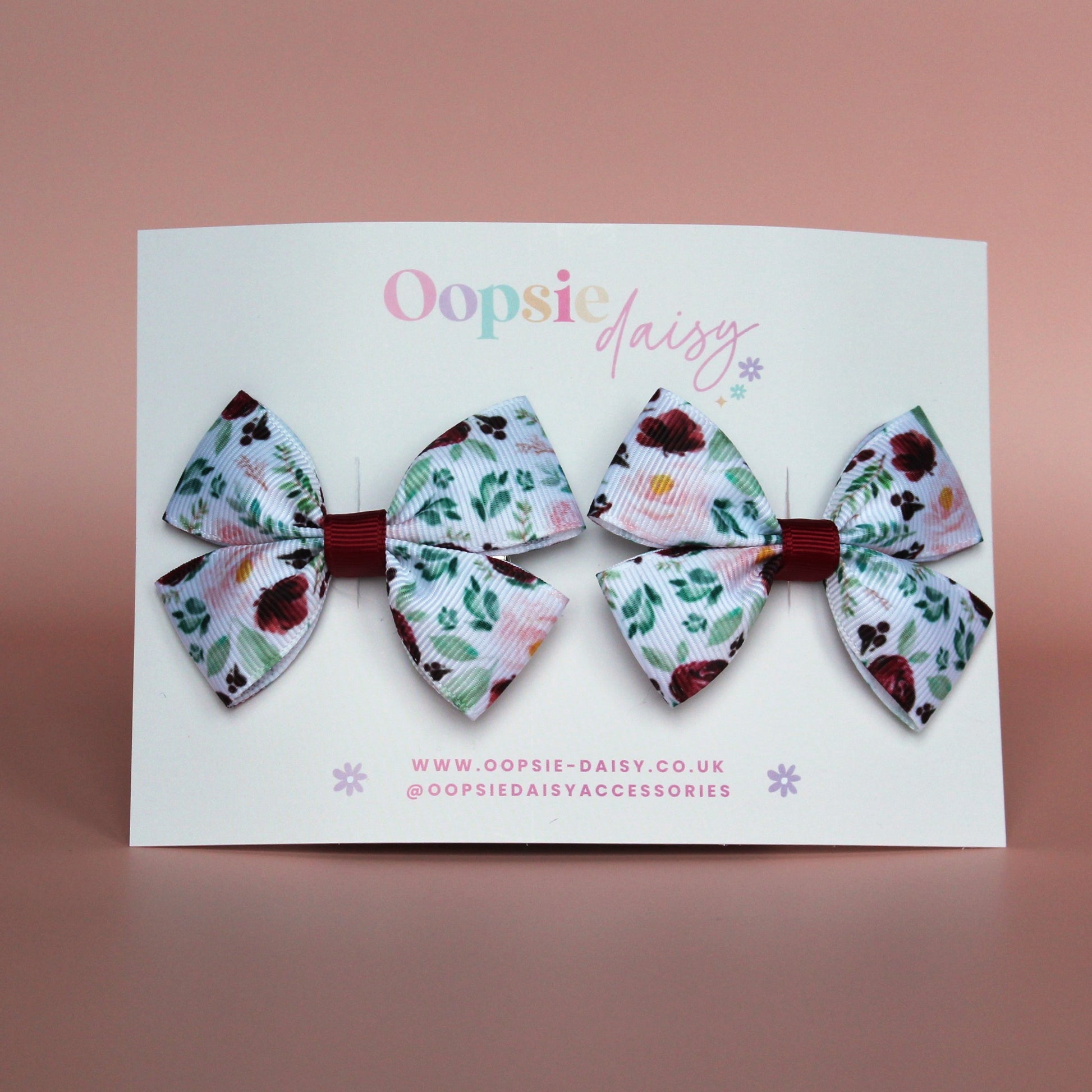 Two bow hair clips with flower pattern in burgundy and pink with green leaves