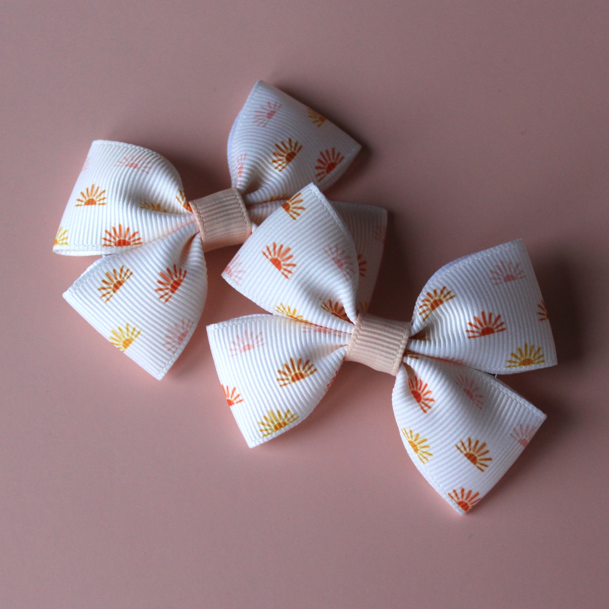 Cream hair bows with subtle orange, pink and yellow little sun pattern