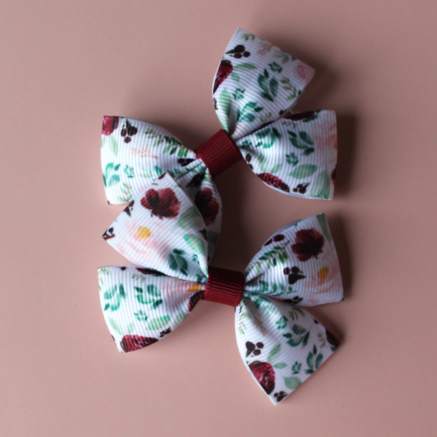 Two bow hair clips with flower pattern in burgundy and pink with green leaves