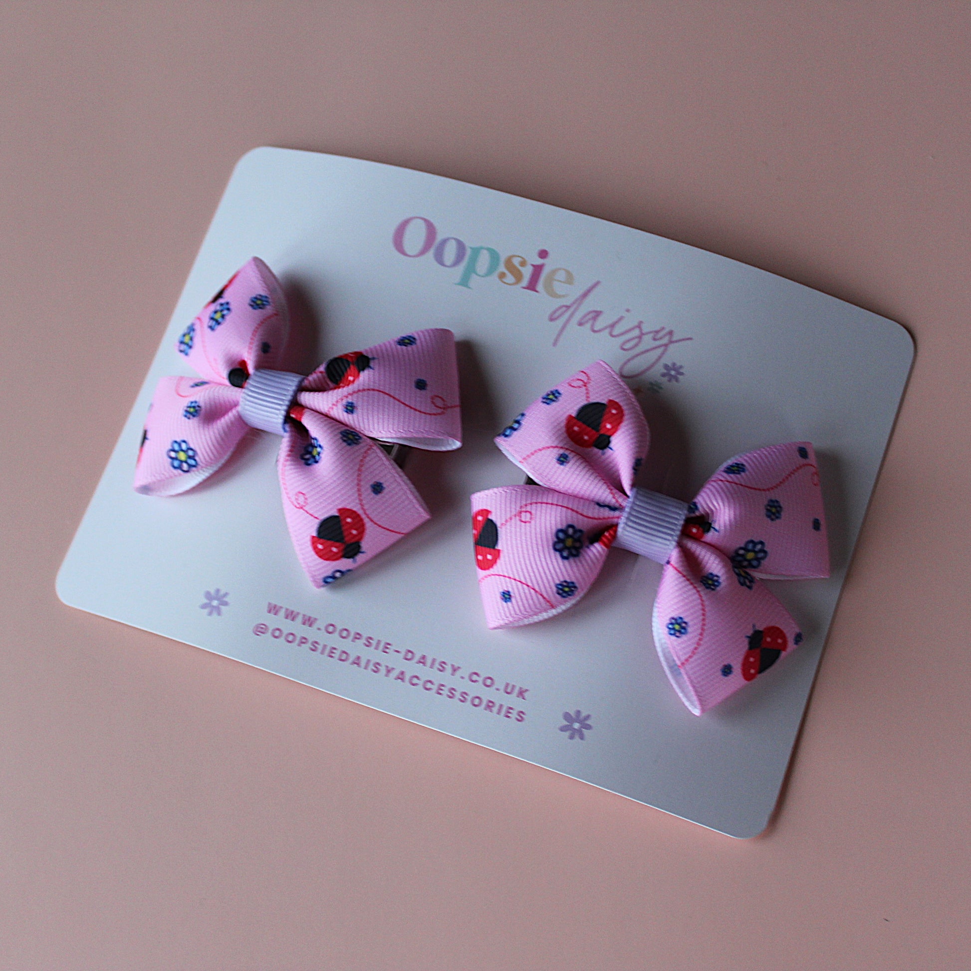 Pink hair bows with red ladybirds and tiny purple flowers