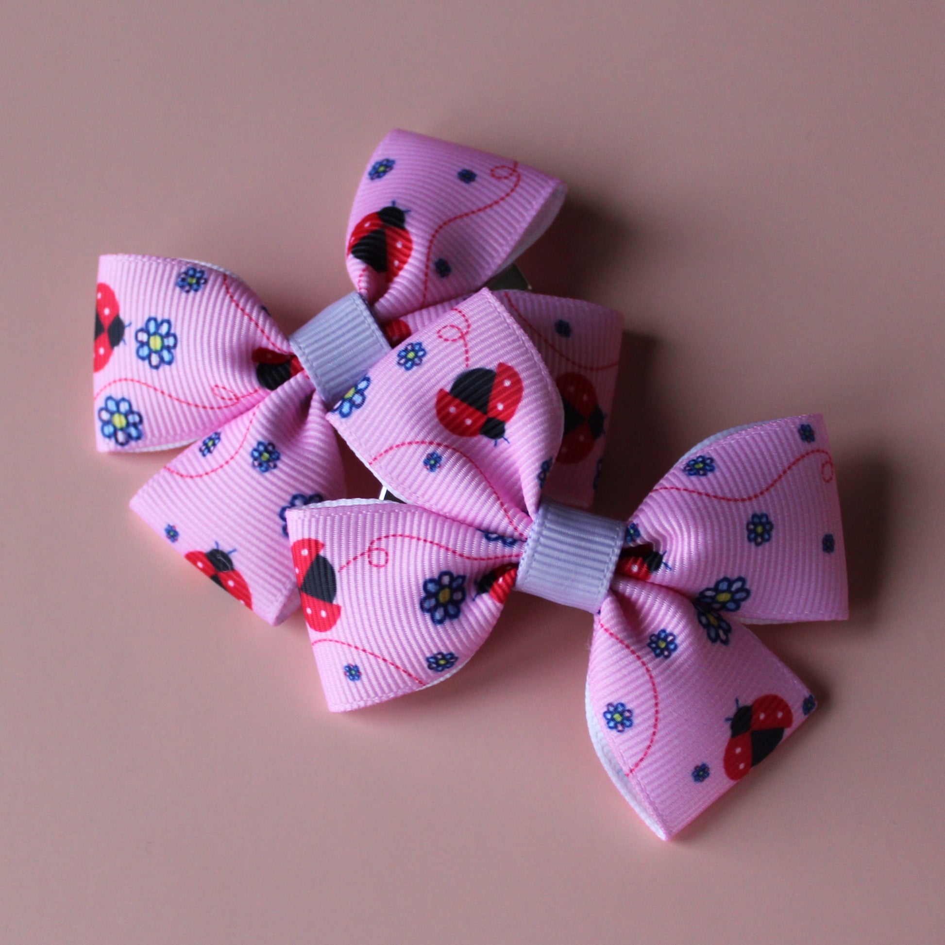 Pink hair bows with red ladybirds and tiny purple flowers