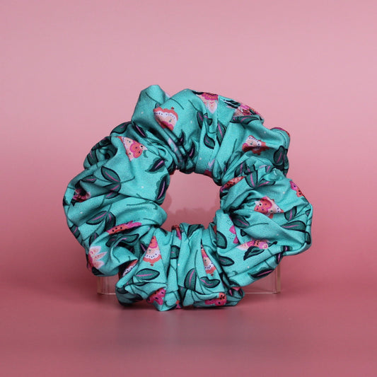 A teal scrunchie with a floral pattern of pink and dark green leaves. 