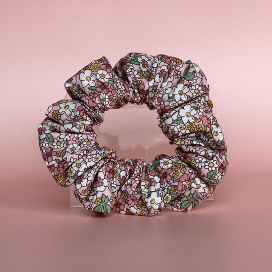 Floral patterned hair scrunchie in pink with white, yellow and green all over pattern. 