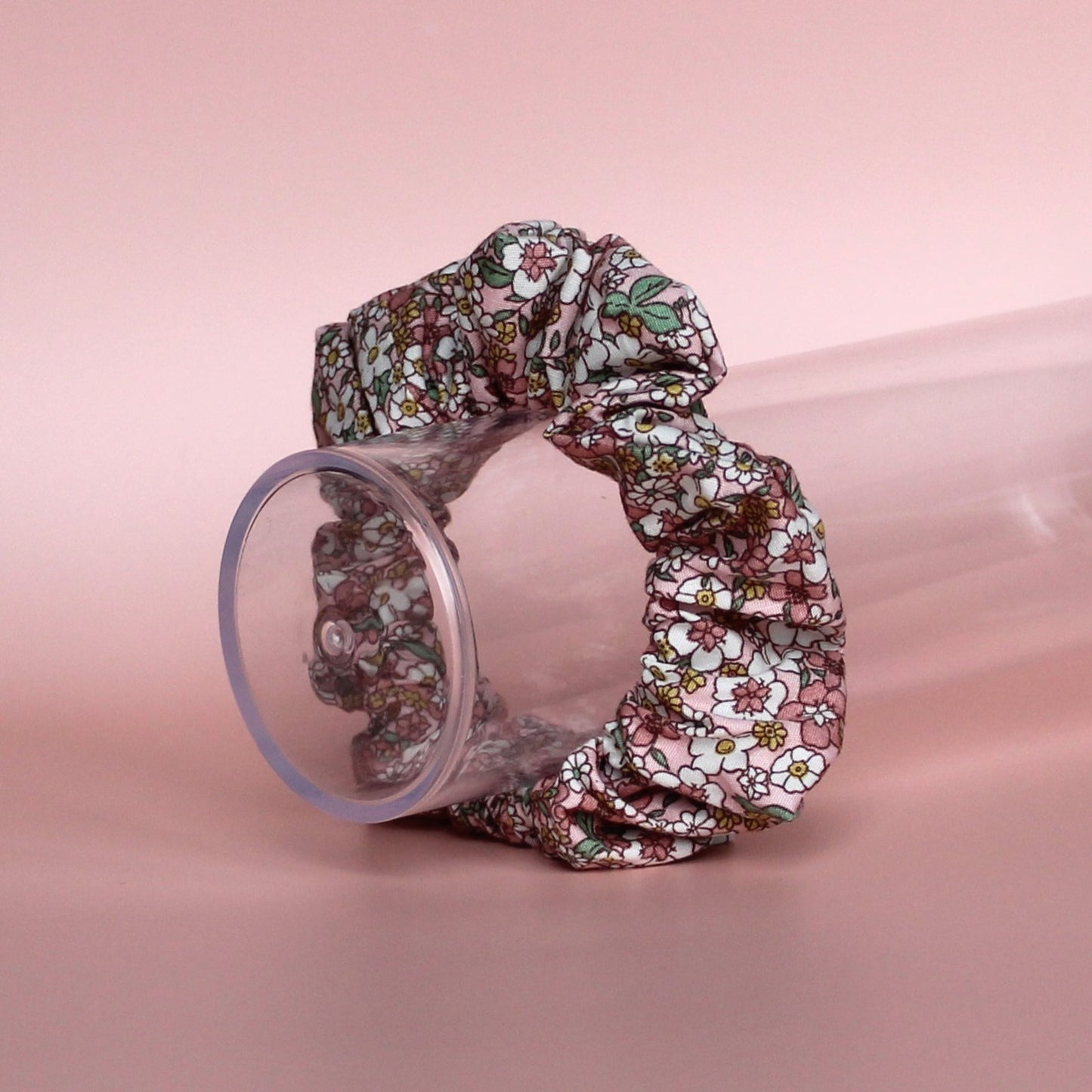 Floral patterned hair scrunchie in pink with white, yellow and green all over pattern. 