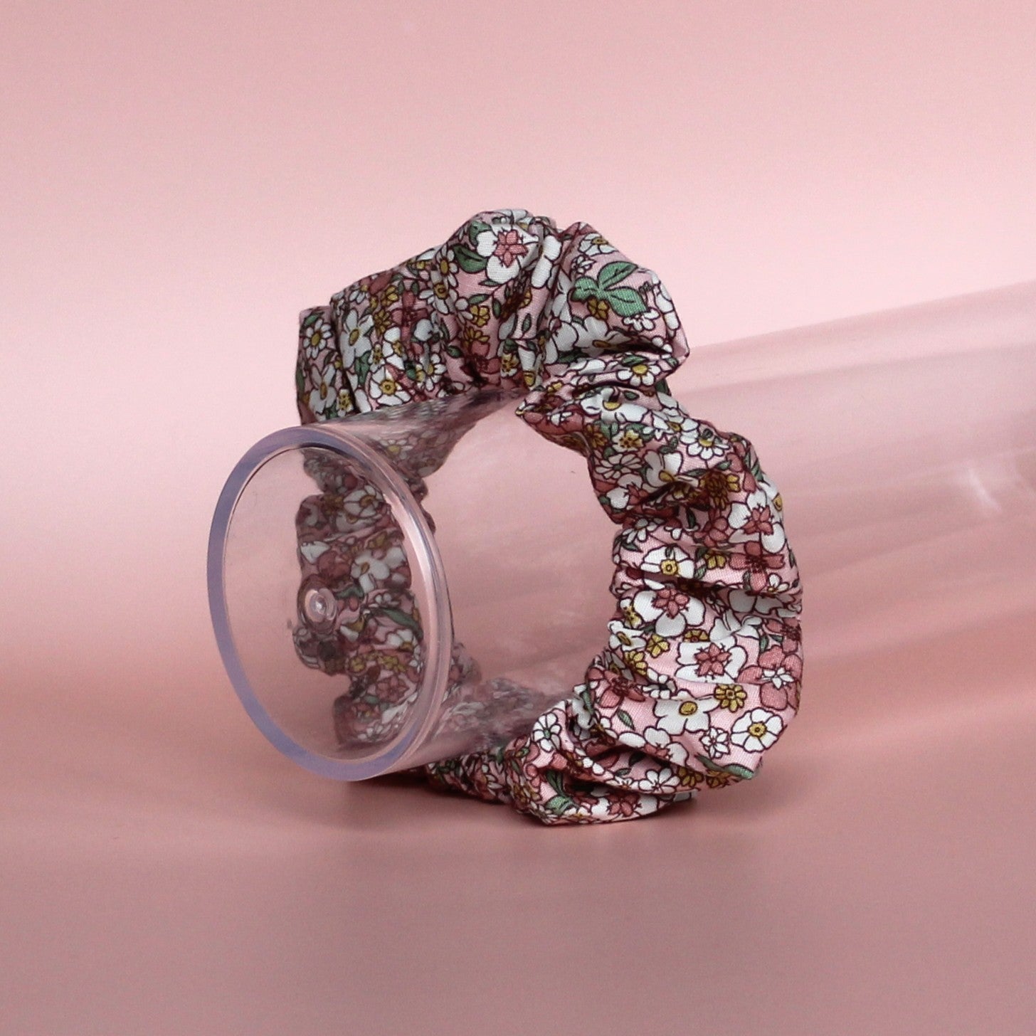 Floral patterned hair scrunchie in pink with white, yellow and green all over pattern. 