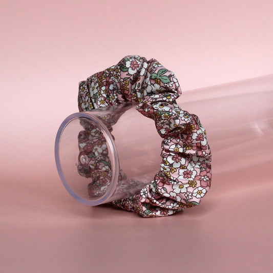 Floral patterned hair scrunchie in pink with white, yellow and green all over pattern. 