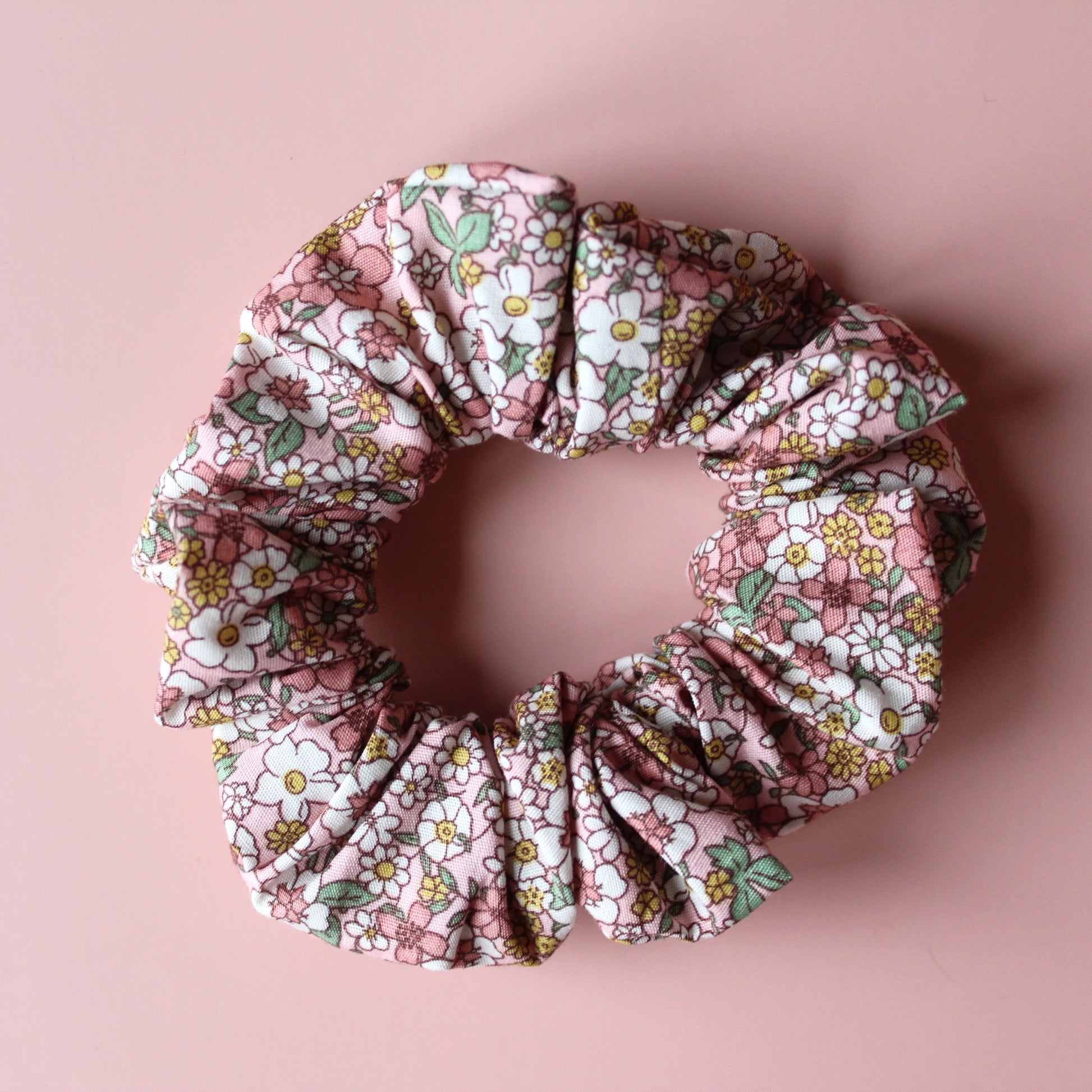 Floral patterned hair scrunchie in pink with white, yellow and green all over pattern. 