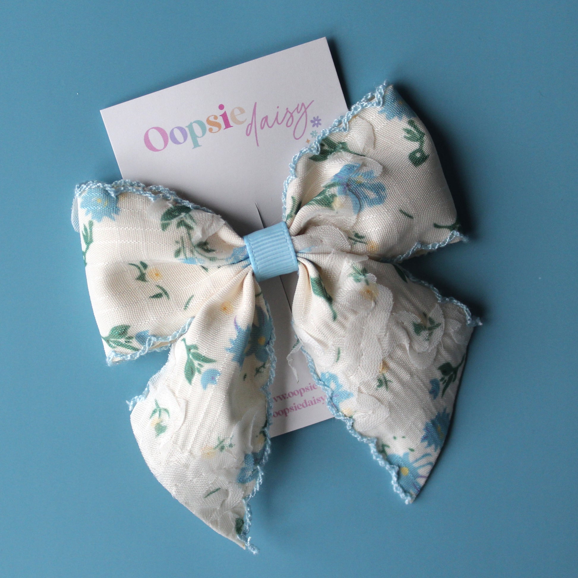 Off-white hair bow with light blue little flowers and light blue trim