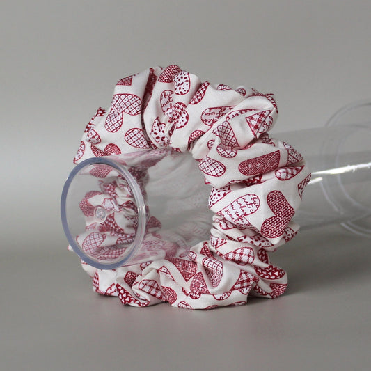 Oversized hair scrunchie with red heart pattern on neutral off-white background