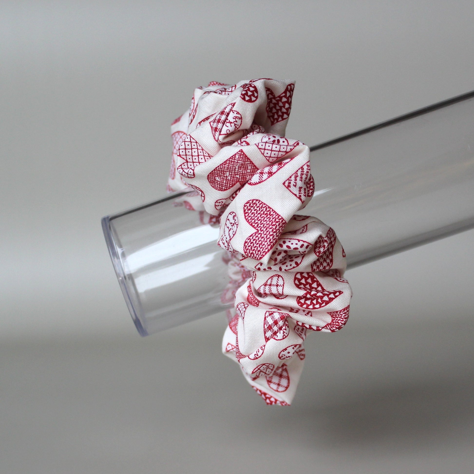 Oversized hair scrunchie with red heart pattern on neutral off-white background