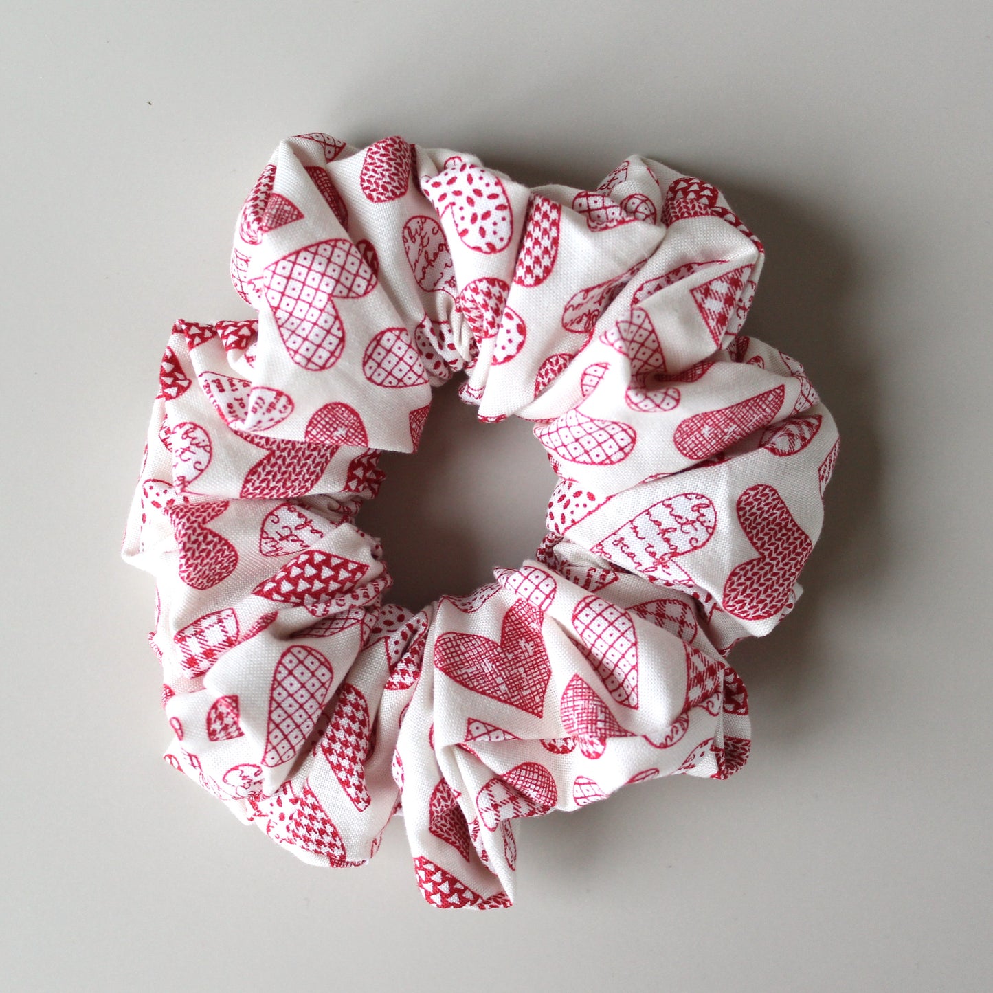 Oversized hair scrunchie with red heart pattern on neutral off-white background