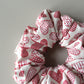 Oversized hair scrunchie with red heart pattern on neutral off-white background