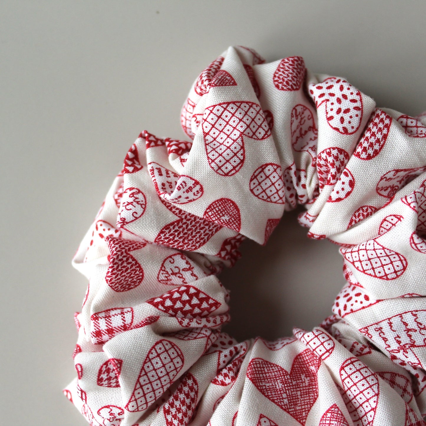 Oversized hair scrunchie with red heart pattern on neutral off-white background
