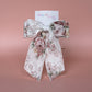 Off-white hair bow with peach coloured floral pattern
